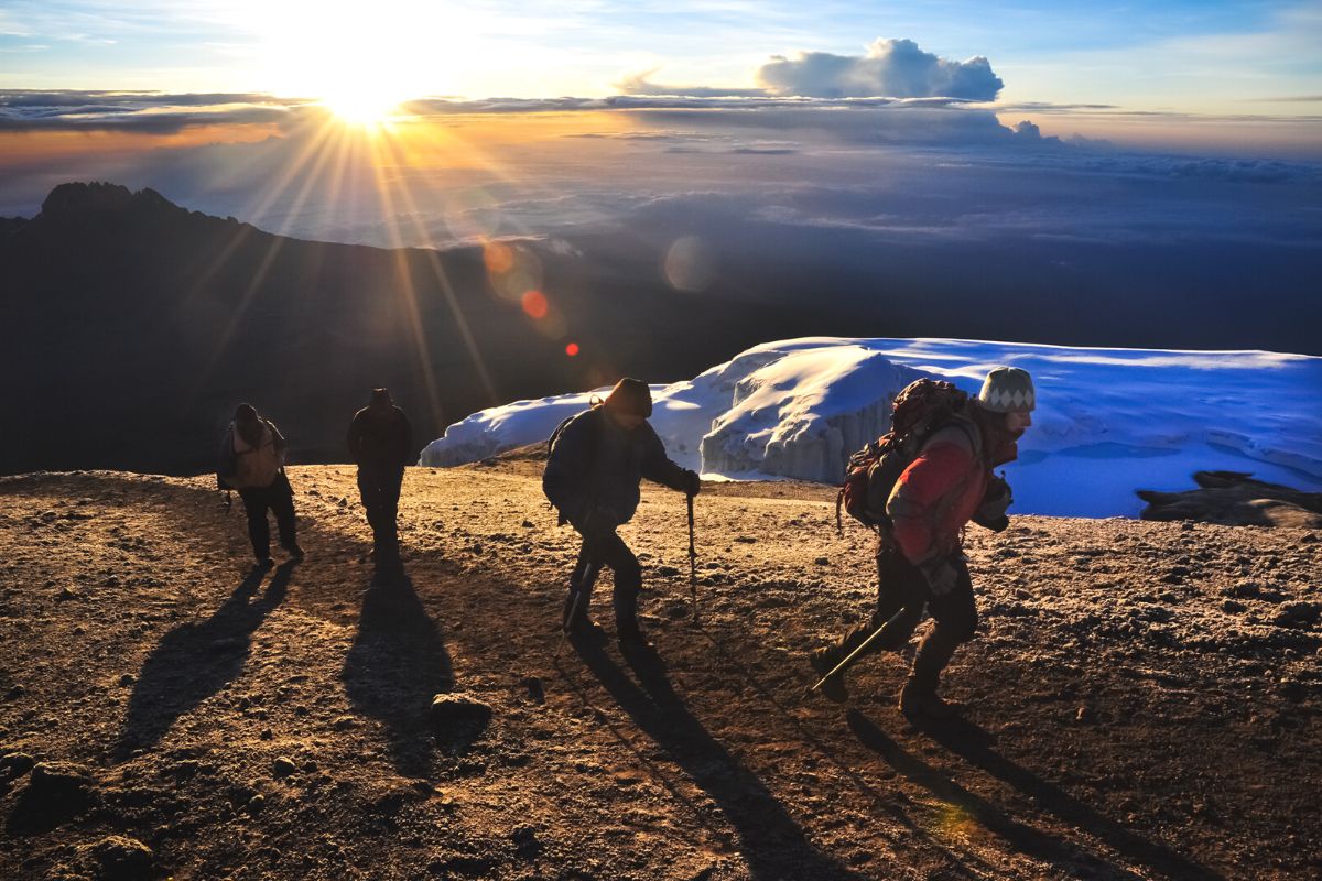 Et hold vandrere på vej op ad Mount Kilimanjaro ved solopgang.