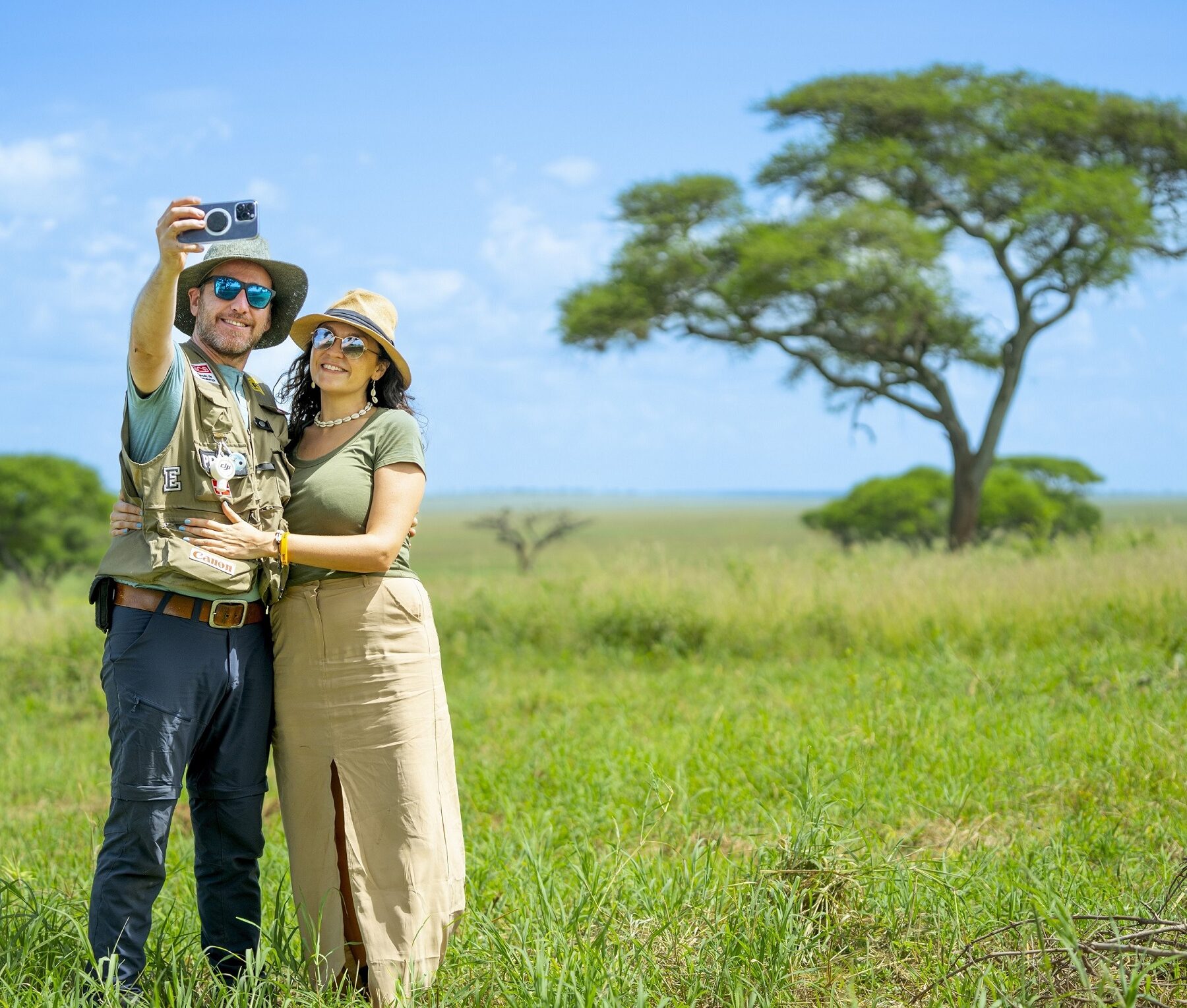 A couple in Tanzania taking a selfie in front of an acacia tree