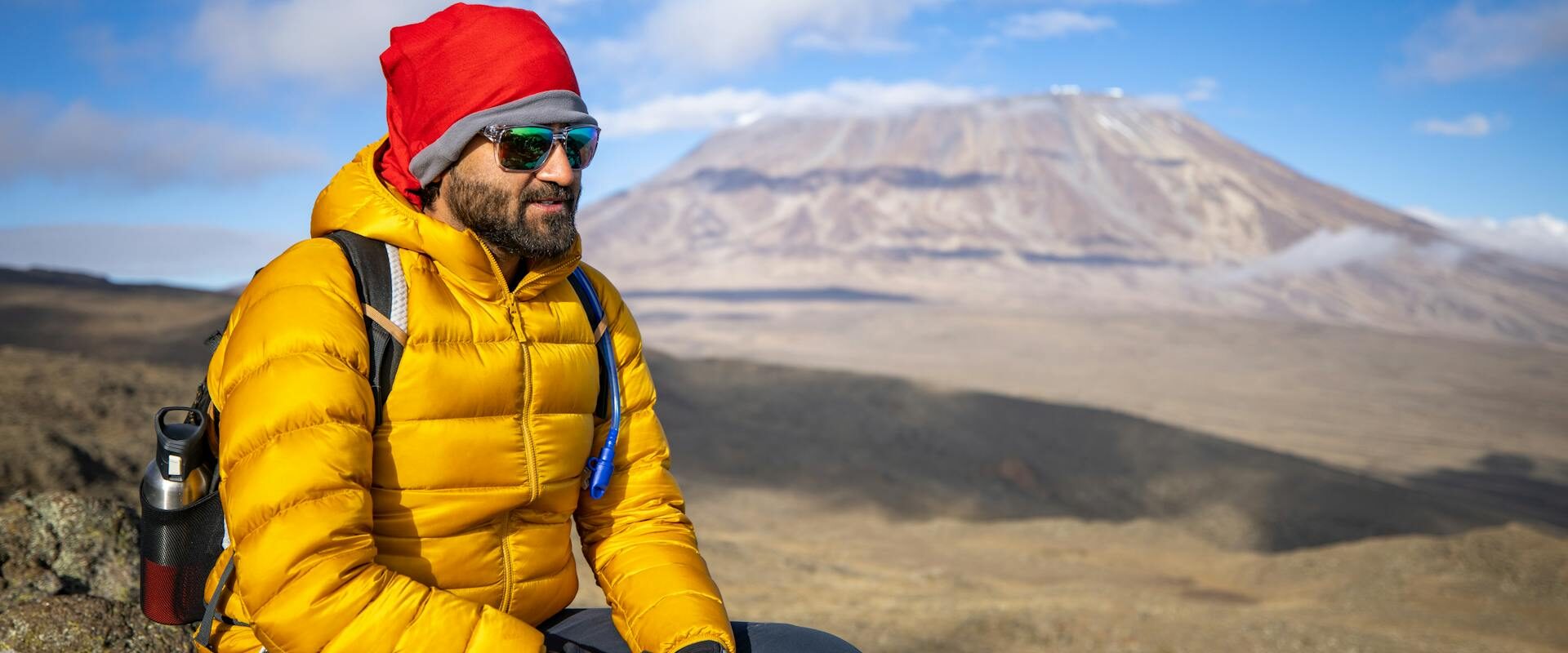 Mand sidder på en klippe under bestigning af Kilimanjaro.